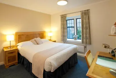 a hotel room with a large bed and a desk at Madingley Hall in Cambridge