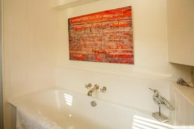 a white bath tub with a painting on the wall at Nutshell in Aldeburgh