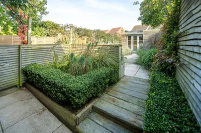 a garden with a wooden walkway next to a fence at Nutshell in Aldeburgh