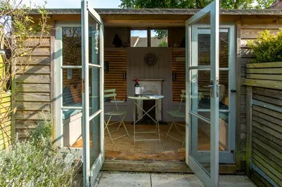 a greenhouse with glass doors in a garden at Nutshell in Aldeburgh