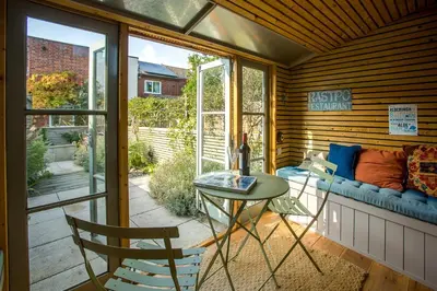 a screened in porch with a table and chairs at Nutshell in Aldeburgh