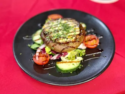a black plate of food with a steak and vegetables at Cross Keys Hotel Chatteris in Chatteris