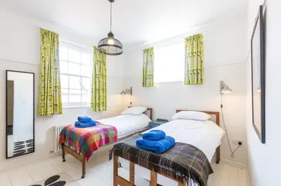two beds in a bedroom with yellow curtains at Watermans in Aldeburgh