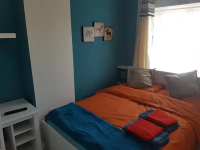 a bedroom with a bed with blue walls and a window at St Giles, Thetford, 2BR House in Thetford