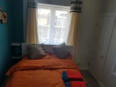 a bedroom with a bed with an orange blanket and a window at St Giles, Thetford, 2BR House in Thetford