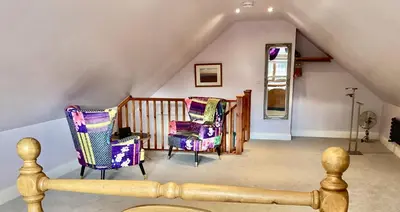 a room with two chairs and a crib in a attic at The little house in West Hanningfield