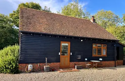 a small blue house with a brown door and chairs at The little house in West Hanningfield