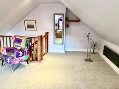 a attic room with a chair and a mirror at The little house in West Hanningfield