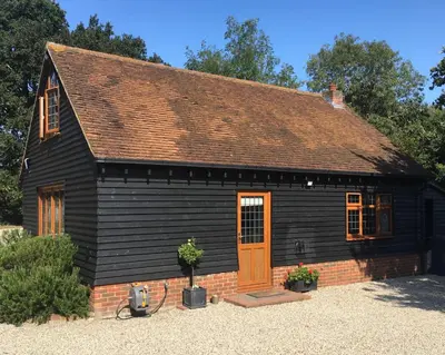 a small black house with a brown door at The little house in West Hanningfield