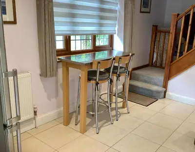 a dining room table with two stools and a window at The little house in West Hanningfield