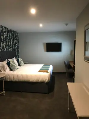 a hotel room with a bed and a flat screen tv at The White Horse in Hertingfordbury