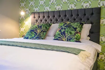a bed with green and white pillows on it at The White Horse in Hertingfordbury