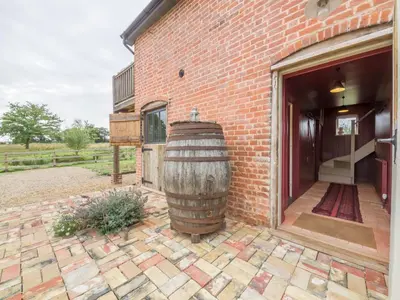 a large wooden barrel sitting outside of a brick building at Snow Hall Barn in Peasenhall