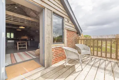 a patio with two chairs on a deck at Snow Hall Barn in Peasenhall