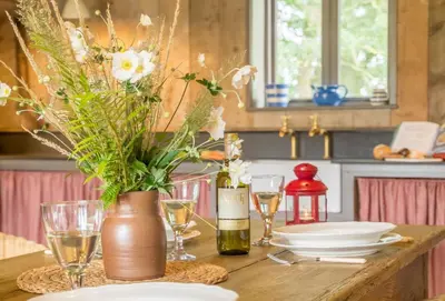 a table with plates and glasses and a vase with flowers at Snow Hall Barn in Peasenhall