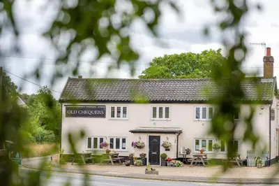 a white building with tables and chairs in front of it at Myrtle Cottage in Friston