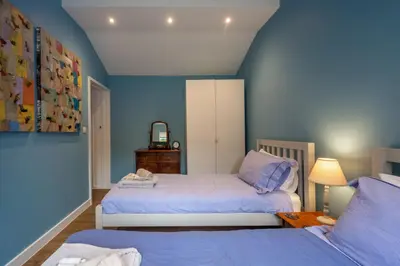 a bedroom with two beds with blue walls at Myrtle Cottage in Friston