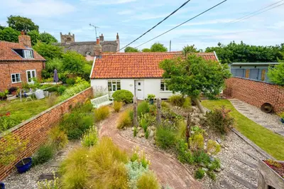 a house with a garden and a brick wall at Myrtle Cottage in Friston