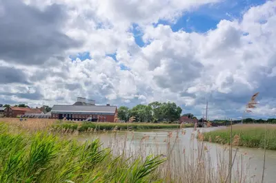a building on the side of a river with a field at Myrtle Cottage in Friston