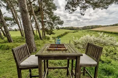 a wooden table with two chairs sitting next to a tree at The Buttery in Freston