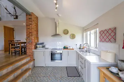 a kitchen with white cabinets and a brick wall at The Buttery in Freston