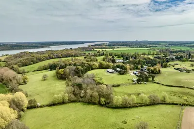 an aerial view of a field with trees and a river at The Parlour in Freston