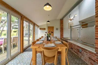 a long wooden table in a room with windows at The Dairy in Freston