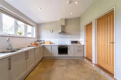 a kitchen with white cabinets and a sink and a window at Lodge Farm in Freston