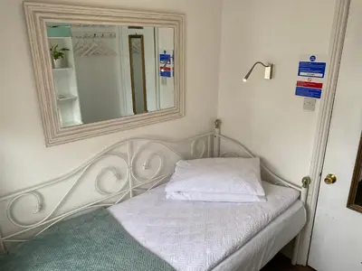 a white bed with a mirror on the wall at A & B Guest House Cambridge Ltd in Cambridge