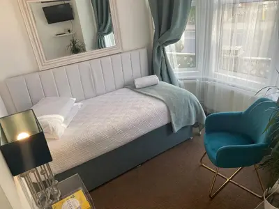 a small bedroom with a bed and a blue chair at A & B Guest House Cambridge Ltd in Cambridge