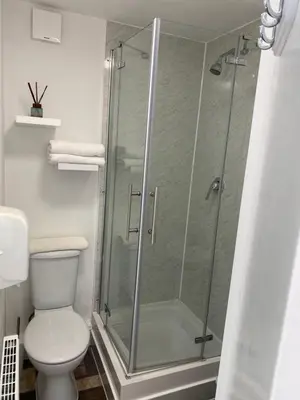 a bathroom with a glass shower with a toilet at A & B Guest House Cambridge Ltd in Cambridge