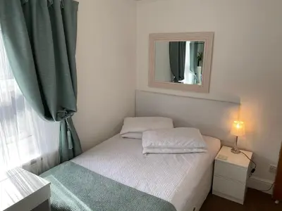 a small bedroom with a bed and a mirror at A & B Guest House Cambridge Ltd in Cambridge
