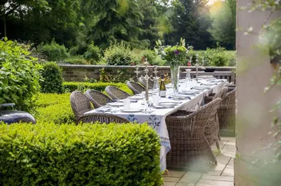 a long table with chairs in a garden at Vicarage House & Pool House in Hockham