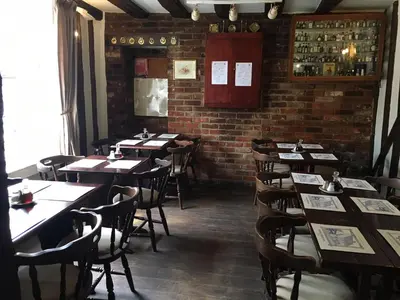 a dining room with tables and chairs and a brick wall at Sorrel Horse Inn in Ipswich