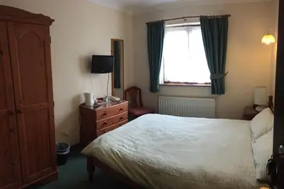 a bedroom with a bed and a dresser and a window at Sorrel Horse Inn in Ipswich
