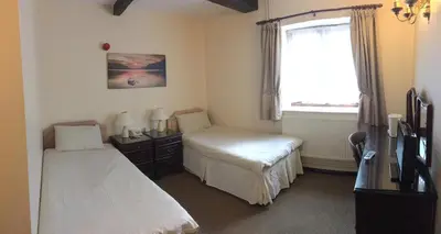 a bedroom with two beds and a window at Sorrel Horse Inn in Ipswich