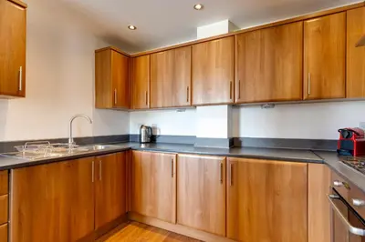 a kitchen with wooden cabinets and a sink at Pass the Keys Spacious and Modern Flat with own Car Park in Cambridge