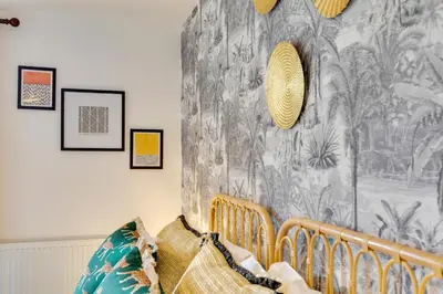a bedroom with a crib and a wall with a wallpaper at Pass the Keys Spacious and Modern Flat with own Car Park in Cambridge