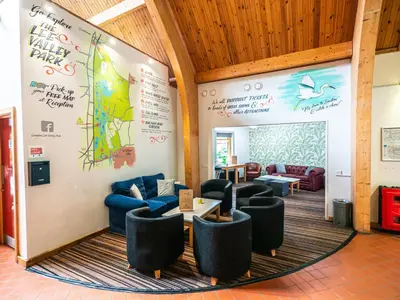 a lobby with couches and a wall with a mural at YHA London Lee Valley in Cheshunt