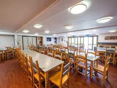 a dining room with tables and wooden chairs at YHA London Lee Valley in Cheshunt