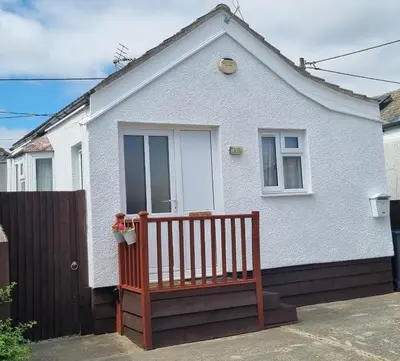 a white house with a bench in front of it at Sandy Cottage in Clacton-on-Sea