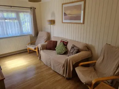 a living room with a couch and two chairs at Sandy Cottage in Clacton-on-Sea
