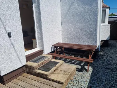 a wooden bench sitting outside of a building at Sandy Cottage in Clacton-on-Sea