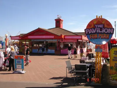 a group of people standing in front of a funfair at Sandy Cottage in Clacton-on-Sea