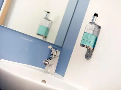 a bathroom sink with a mouthwash bottle on a mirror at YHA Cambridge in Cambridge