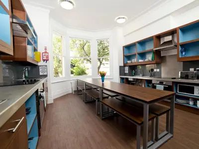 a kitchen with a long table and blue cabinets at YHA Cambridge in Cambridge
