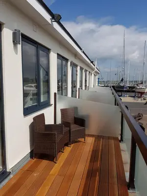a balcony with two chairs on a building with a marina at The Shipwreck Loft in Shotley Gate