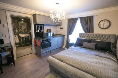a bedroom with a bed and a kitchen with a clock at Apartments at Number 10 The Abbey in Norwich