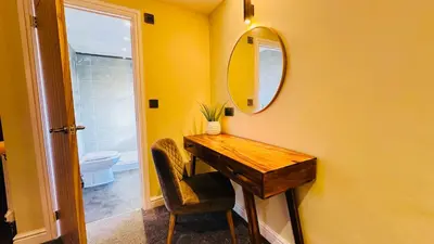 a bathroom with a wooden table and a mirror at The Suffolk Hotel in Haverhill