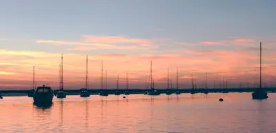 a group of boats sitting in the water at sunset at The retreat in West Mersea